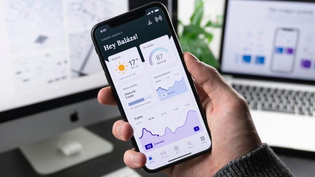 A phone showing an app beside a laptop